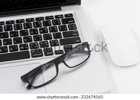 Blank business laptop, mouse and glasses on white table