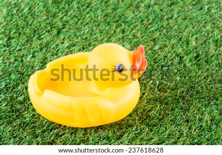 Yellow rubber duck on green grass background