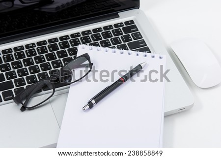 Blank business laptop, mouse, pen, glasses and note on white table