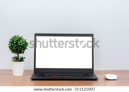 Black laptop on wooden table on white wall