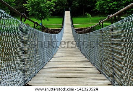 Swinging footbridge beckons the adventurous hiker to discover what lies on the other side. Swinging Bridge Park. Croswell, Michigan.