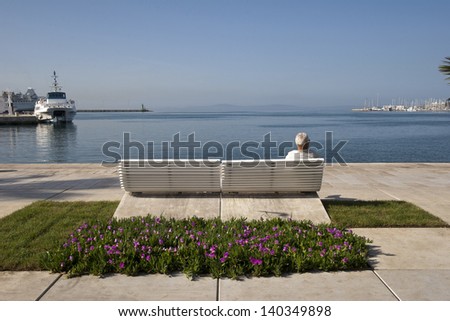 Old man on the bench on Split coast with view on blue sea and boats in the harbor
