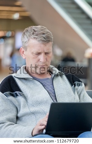 man the passenger with the laptop in a waiting room of the modern station