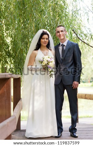 groom and the bride cost on the wooden bridge in a summer garden
