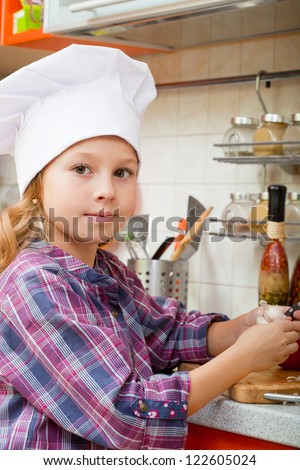 girl in a cook cap helps to make a dinner.