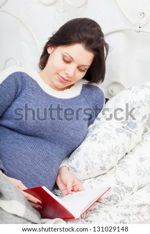 pregnant woman reads the book, lying in a bed