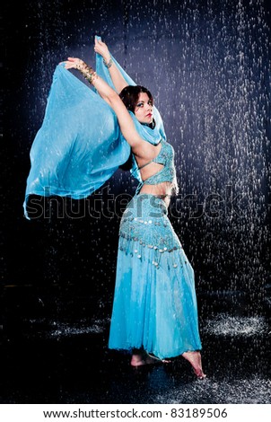 girl executes east dance in the rain against a dark background