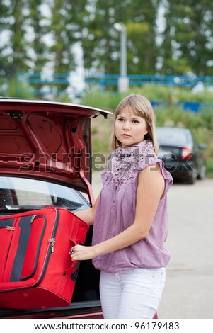 Blonde woman packing her baggage into the car