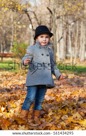 little girl in a coat walks in autumn park