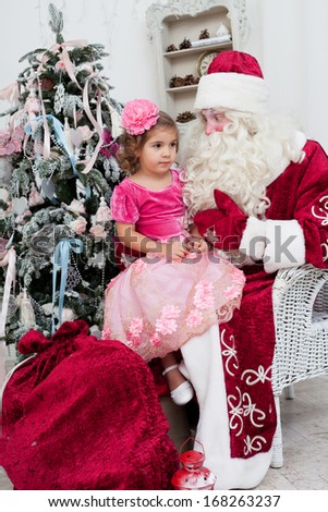 little girl in a beautiful dress sits on a lap at Saint Nicolas about a New Year tree