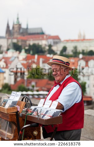 PRAGUE, CZECH REPUBLIC - JULY 30, 2013: Man offers music from hand operated music box in exchange for money on Charles Bridge in Prague, Czech Republic