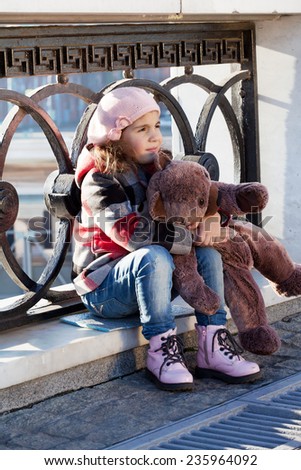 Little girl in a pink beret holds a toy bear