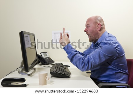 Angry worker give finger to his computer.