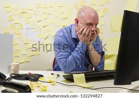 A frustrated office worker looking at his computer monitor.