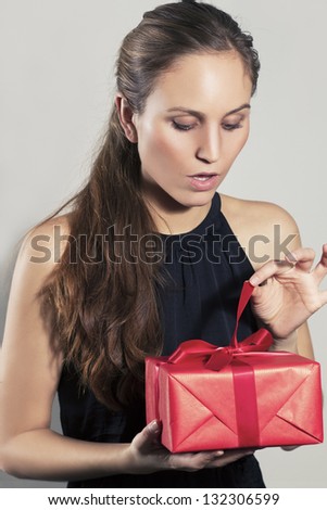 Excited young pretty woman open christmas gift or birthday present. Gray background. Copyspace.