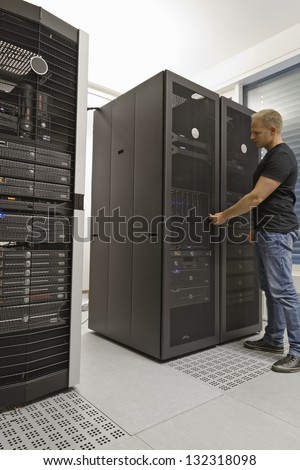 It engineer / consultant working in a data center. Opening a server rack door.