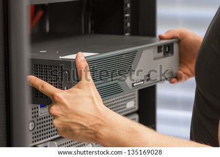 It engineer / consultant install / inserts a router / switch in a rack. Shot in a data center.