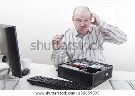 Office worker / businessman with computer / IT problems with a memory component in his hand.