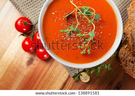 Fresh gourmet tomato soup with fresh herbs and pepper. Bread, oregano and tomatoes on the side.
