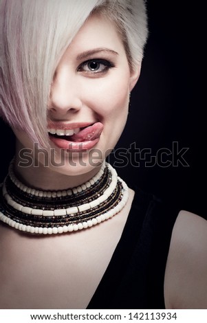 A glamorous and elegant young woman with creative hair style and her tongue out.