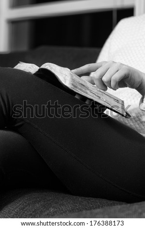 Close-up of a christian woman reading the holy bible. Sitting in sofa. Black and white.