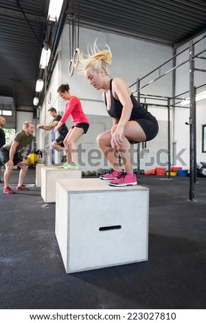 Workout group trains box jumps at the fitness gym