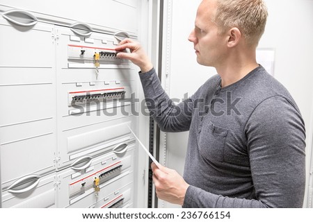 Technician works in large electric fuse cabinet