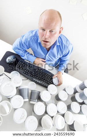 Tired businessman drinks too much coffee at office