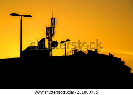 Roofs of buildings with many antennas in a big city at sunset make silhouettes