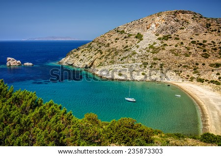 Bay in Syros island, Cyclades, Greece, with clear transparent waters and an anchored sailing boat.