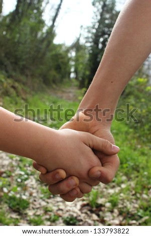 kids hand by hand in the green path