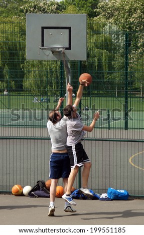 LONDON, ENGLAND - MAY 5, 2014: Men play basketball in a local park. Physical activity levels are low in the UK. In England, 66% of men and 56% of women claim to meet the CMOsÃ¢Â?Â? recommendations