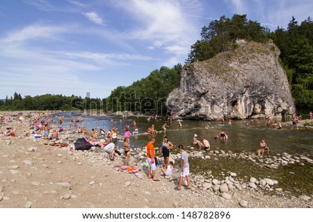 NOWY TARG - AUGUST 4: Biala river full of people during a hot day near Nowy Targ on 4 August 2013. Water in Biala river is always cold as it is a melted snow in Tatra mountains.