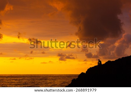 People in a shadow against sunset light with a sea in the background