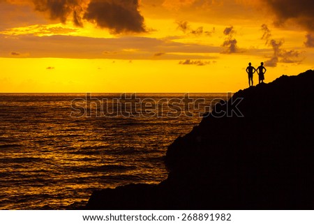 People in a shadow against sunset light with a sea in the background
