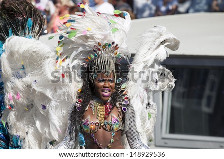 AMSTERDAM, THE NETHERLANDS - AUGUST 3, 2013: Dark lady with with white feathers dance in front of spectators at the famous Canal Parade of the Amsterdam Gay Pride 2013 on August 3, 2012 in Amsterdam.