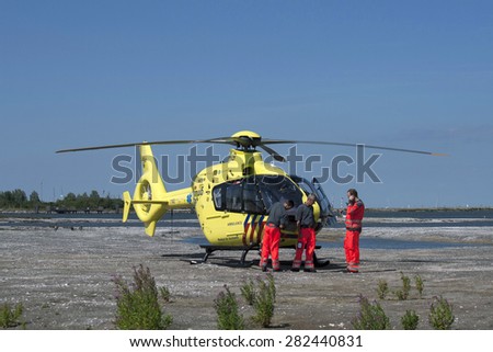 MEDEMBLIK ,NETHERLANDS - AUGUST 12, 2013: Medical dutch rescue helicopter and three medical people ready for takes off on 12 augustus ,2012 in Medemblik, Netherlands.