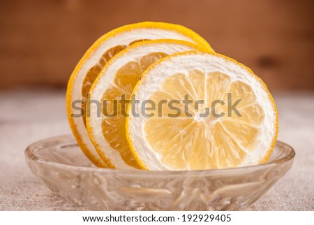 Macro shot of lemon cut to slices on little plate on table covered with rough textile