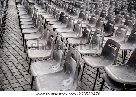 Rows of empty plastic seats on stone pavement, outdoor setting