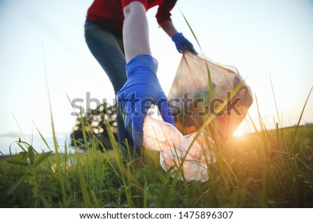volunteer young woman collecting garbage, picking up waste at sunset light, land pollution, environmental problem Foto stock © 