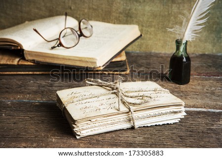 old letters, books, glasses and an ink bottle with a quill on vintage wood