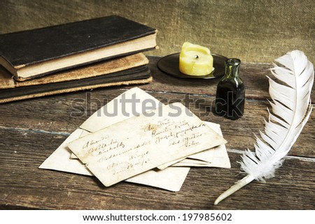 old letters, books, candle, an ink bottle and a quill on vintage wood
