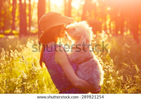 young girl holding her dog, rural sunny landscape