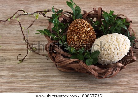 Easter decorations / cards hand-decorated Easter eggs covered in rice and buckwheat with boxwood in a nest made of rattan on a wooden background / on the table with willow sticks