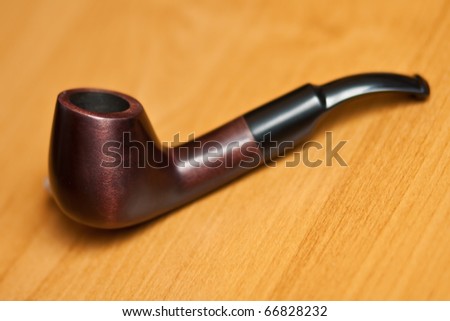 Original smoking pipe on wood background. Selective focus.
