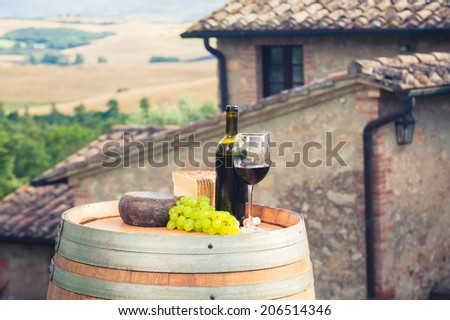 Red wine, pecorino cheese on a wooden barrel in the background of the Tuscan landscape, Italy