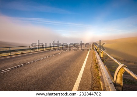 Long bridge in the fog, between fields