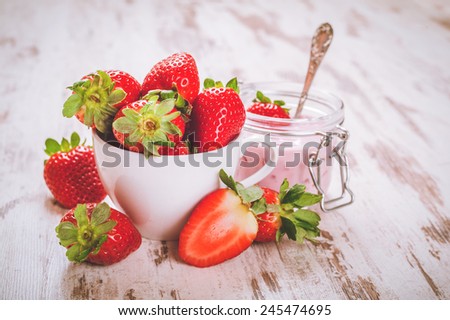 Spring fruits, strawberries with strawberry yogurt on a vintage wooden table.