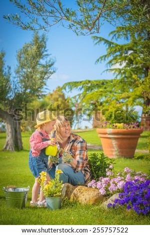Beautiful little girl with a smile helps his mother in the work of gardening.