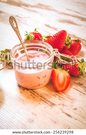 Spring fruits, strawberries with strawberry yogurt on a vintage wooden table.